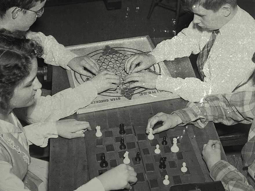 Young people playing chess and Chinese Star Checkers at a table in the 1940s